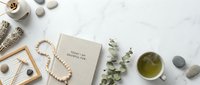 Flat lay composition with natural elements, jewelry, tea cup and inspirational book on white marble surface for lifestyle branding and wellness content.