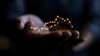 Magical glowing mountain silhouette floating above cupped hands in dark atmosphere with sparkly light trail effect creates mystical fantasy scene.