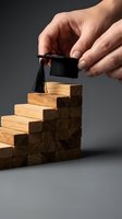 Hand placing graduation cap on wooden blocks staircase representing educational achievement and academic success journey.
