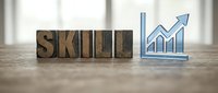 Wooden letter blocks spelling SKILL next to upward trending graph chart on desk, representing professional development and career growth in business.
