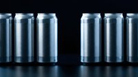 Aluminum beverage cans arranged in rows on dark surface with dramatic lighting creating reflections and shadows for packaging design concepts.