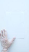 Hand wearing transparent disposable glove on clean white surface for medical safety hygiene protection and contamination prevention in healthcare settings.