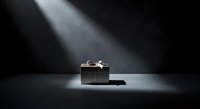 Luxury gift box with silver ribbon on dark surface under dramatic spotlight lighting, suitable for holiday, celebration, and premium product marketing campaigns.