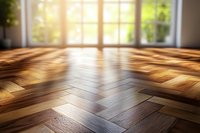 Empty room with herringbone parquet flooring and bright natural sunlight streaming through large windows creating warm golden light patterns on wooden floor.