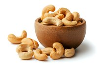 Raw cashew nuts in wooden bowl and scattered on white surface. Natural healthy snack rich in protein and healthy fats for vegetarian nutrition and cooking.