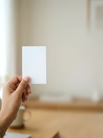 Hand holding blank white card in modern interior space with natural light, suitable for business branding and marketing mockups.