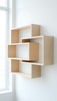 Modern geometric wooden wall shelves in light oak finish mounted on white wall near window for contemporary home decor and storage solutions.