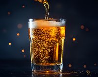 Golden beer pouring into glass with bubbles and foam against dark background with bokeh lights, showcasing refreshing beverage.