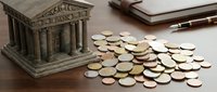 Miniature bank building with scattered coins on wooden desk surface representing financial savings and investment concepts for business presentations.