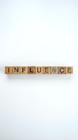Wooden letter blocks spelling INFLUENCE on white background for business marketing and social media concepts.