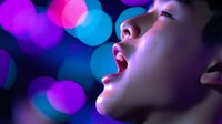 Young Asian woman singing passionately with colorful bokeh lights in background, entertainment performance concept for music and nightlife projects.