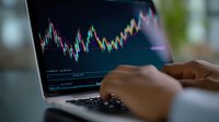 Financial market analysis on laptop screen showing colorful trading chart with stock price movements and technical indicators for investment decisions.