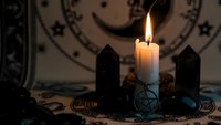 Mystical altar setup with burning candle, crystals, pentagram and zodiac wheel for spiritual rituals, divination and occult practices.
