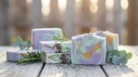 Handmade natural soap bars with lavender and eucalyptus on rustic wooden surface with soft bokeh lighting for spa and wellness aromatherapy concepts.