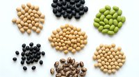 Assorted legumes and beans collection featuring soybeans, black beans, green peas, and speckled varieties arranged on white background for cooking recipes.