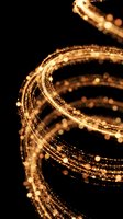 Golden light trails with sparkling particles flowing in curved motion against black background creating magical energy waves for luxury design projects.