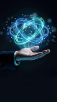 Businessman hand holding glowing blue atomic structure with energy rings and particles on dark background for technology and science concepts.