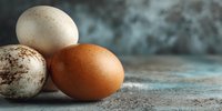 Fresh farm eggs with speckled shells on rustic wooden surface for organic cooking and healthy breakfast preparation.
