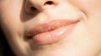 Close-up of woman's lips with natural nude pink tone and glossy finish, showcasing cosmetics, beauty products, and skincare results for makeup advertising.