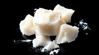 Fresh white coconut meat chunks with shredded flakes on black background for healthy cooking and tropical cuisine recipes.