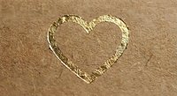 Heart shape drawn in golden beach sand with warm sunlight creating romantic seaside atmosphere for love and vacation concepts.