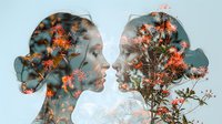 Young woman and man silhouettes in profile with double exposure effect featuring blooming orange flowers and branches against blue sky, romantic nature concept.