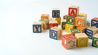 Colorful wooden alphabet blocks scattered on white background, educational toys for children learning letters and numbers, preschool development tools.