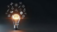 Glowing light bulb with brain inside surrounded by floating innovation icons on dark background representing creative thinking and business ideas.