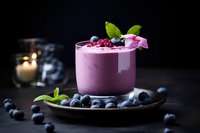 Purple blueberry smoothie in glass with fresh berries and mint garnish on dark wooden surface with candle creating moody atmosphere for healthy lifestyle.