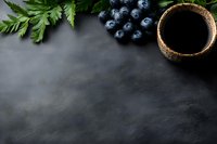 Fresh blueberries and green leaves arranged with ceramic cup of black coffee on dark stone background with copy space for menu or recipe design.