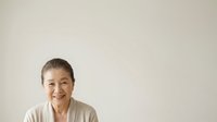 Mature woman with short gray hair and fair complexion smiling at camera against neutral background, suitable for healthcare, wellness, senior lifestyle and corporate portraits.