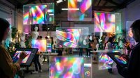 Young diverse professionals and visitors engaging with interactive holographic displays featuring vibrant rainbow light projections at a modern tech exhibition or digital innovation conference venue.