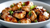 Glazed meatballs with fresh herbs in white bowl, savory appetizer dish with caramelized coating and green garnish for restaurant menu and cooking content.