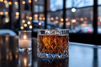 Crystal whiskey glass with amber liquor on bar counter with warm bokeh lights and urban evening atmosphere creating luxury drinking experience.