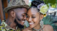 Happy African American couple sharing intimate moment outdoors with natural lighting and floral hair accessories for wedding or engagement photography.