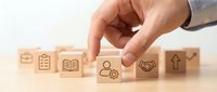 Hand selecting wooden cube with person and gear icon from business concept blocks on desk representing human resources management and team development.