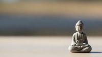 Peaceful Buddha statue in meditation pose on wooden surface with soft blurred background for mindfulness and spiritual wellness concepts.