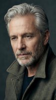 Distinguished mature Caucasian man with silver hair and beard wearing olive green coat against dark background for professional headshot photography.