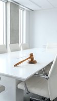 Wooden gavel on white conference table in modern law office meeting room with natural light for legal consultation and attorney services.