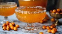 Orange cocktail with salt rim in vintage coupe glass surrounded by fresh kumquats on marble surface, selective focus with blurred background creates festive mood.