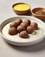 Homemade meatballs served in creamy sauce with mustard and spices in wooden bowls on light background, traditional cuisine.