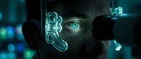 Young male with glowing cyan eyes examining holographic digital interface with neon light projections in dark futuristic setting. Technology and innovation concept.