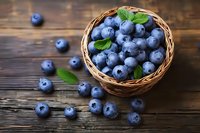 Fresh ripe blueberries with green leaves in woven basket on rustic wooden table background, scattered berries around, macro food photography.