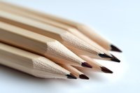 Sharp wooden pencils arranged in diagonal composition on white background, macro photography showing texture and graphite tips, minimalist office supplies setup.