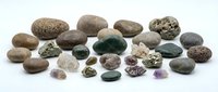 Collection of various natural stones and minerals including amethyst, pyrite, and pebbles arranged on white background, isolated for design use.