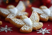 Gingerbread angel cookies with white icing wings on festive red background with snowflakes and warm bokeh lights for holiday baking and Christmas celebrations.