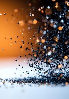 Black particles floating against orange background with bokeh light effects, creating dynamic motion and depth in macro photography composition.