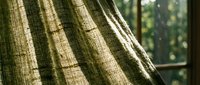Olive green striped linen curtain fabric with natural texture, draped near window with soft daylight filtering through, suitable for interior design and home decor projects.