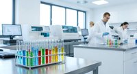 Modern laboratory with colorful test tubes and scientists in white coats conducting research experiments in bright sterile environment for medical analysis.