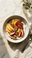 Creamy yogurt bowl topped with fresh sliced peaches, apples, and crunchy granola on marble surface. Healthy breakfast or dessert option.
